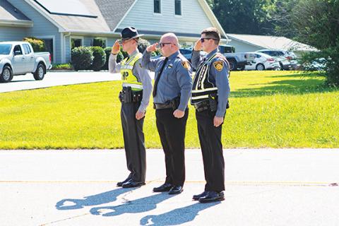Cannon Crompton/sports@cherokeescout.com A Highway Patrol trooper and two Swain County sheriff’s deputies (from left) salute as the funeral procession for Transport Detention Officer Francisco Flattes drives by.
