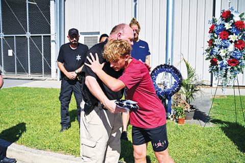 Photos by Michelle Bradbeer/Staff Correspondent Andrew Collinson and Cherokee County sheriff’s Capt. David Williams embrace during an event Saturday morning to honor fallen Detention Transportation Officer Francisco Flattes.