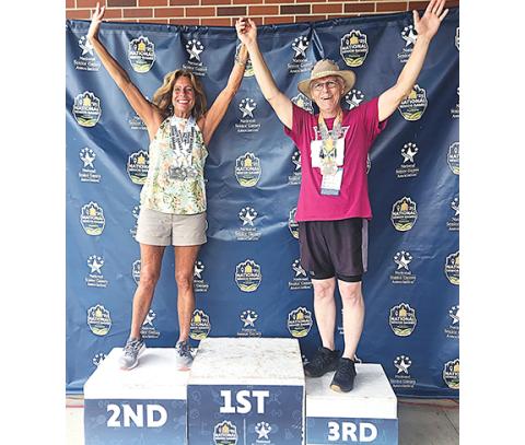 Julia Faries/ Contributing Photographer Michele Preisser (left) and Terence Faries stand on the podium at the National Senior Games at Iowa State University in Des Moines, Iowa.