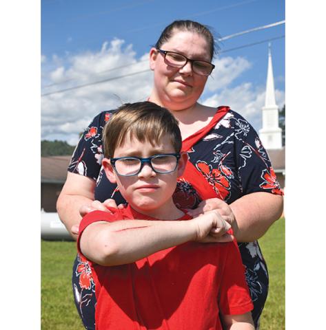 Nathaniel Johnson, 8, with his mother, Felisha Johnson, shows off the cut he suffered trying to rescue cats from a fire. Nathaniel saw the smoke and alerted his family and others, hastening their escape