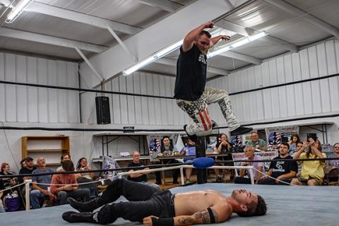 Cannon Crompton/sports@cherokeescout.com Kevin Seiber looks to land an elbow drop from the ropes on Flex Ferguson during the ACWF show on Aug. 2 as a sold-out crowd looks on in Peachtree.