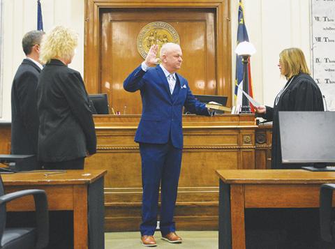Photos by Randy Foster/editor@cherokeescout.com Chris Wood (center) swears on a Bible his oath of office administered by Superior Court Judge Tessa Sellers (right) with his wife Vivian (left) at the Cherokee County Courthouse on Monday morning.