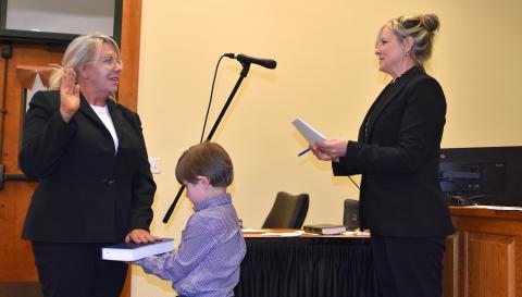 Jeana Conley (left) takes the oath of office administered by Maria Hass, clerk to the board of commissioners, as family friend Harper Hammond, 4, holds the Bible.