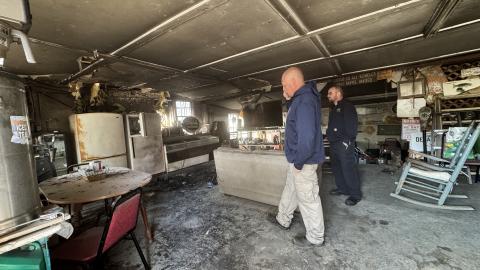 Clay County Fire Chief Brian Henderson (left) takes a phone call as assistant fire chief Chris Denton stands by inside Clay’s Corner in Brasstown, which was damaged in a fire Friday afternoon.
