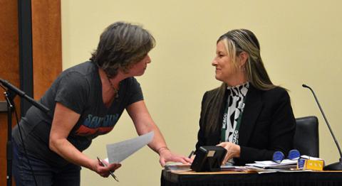 Randy Foster/editor@cherokeescout.com Cherokee County resident Katherine Taaffe (left) presents a petition to Maria Hass, clerk to the Cherokee County Board of Commissioners, calling for the county to protect public lands from private development at the Feb. 16 board of commissioners meeting.