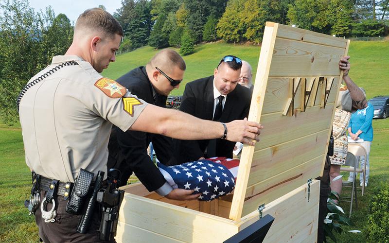 Members of the Cherokee County Sheriff’s Office place the remains of Deputy K-9 Ajax into a coffin that was buried at the law enforcement training center in Marble. Photos by Penny Ray