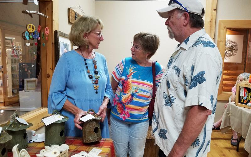 At the Fall into Art festival Friday during the Art Walk, Cathy Mozley tells Debbie and Jerry Cromer of Edisto Beach, S.C., about her ceramic bird houses.
