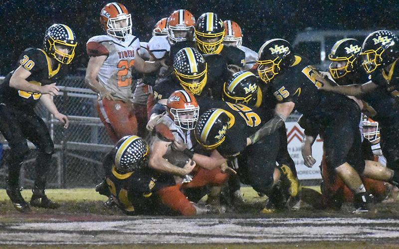 Murphy defenders pile on a Rosman ballcarrier in the mud Friday night.