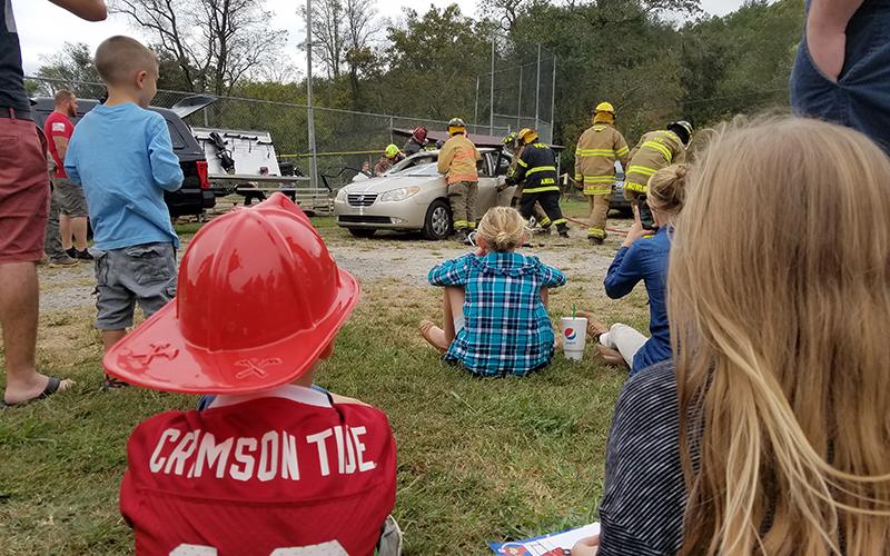 Children watch as teams of volunteer firefighters practice extraction skills and show the difference in tools during the Car Extraction Race at the Ranger Volunteer Fire Department on Saturday. "They're ripping the doors off?" one child exclaimed as the volunteers carefully removed pieces of the car.