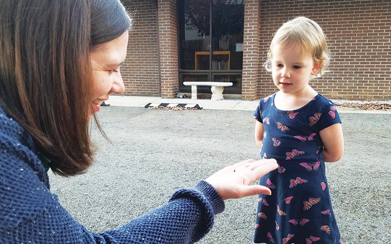 North Carolina Arboretum ecoExplore coordinator Libbie Dobbs-Alexander explains to 3-year-old Cora Dance of Murphy that the bug she found on the library grounds is a ladybug larva.