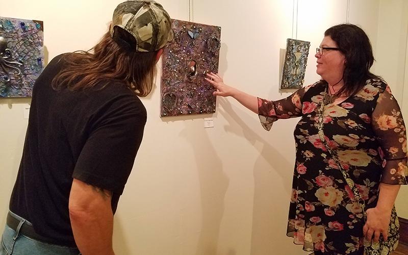 Marie Gunther points out shotgun shells used in her three dimensional piece "Through a Glass Darkly" to Tom Vogler. The piece was on display at the Andrews Art Museum on the second floor of the Valleytown Cultural Arts Center during Writers & Wine.