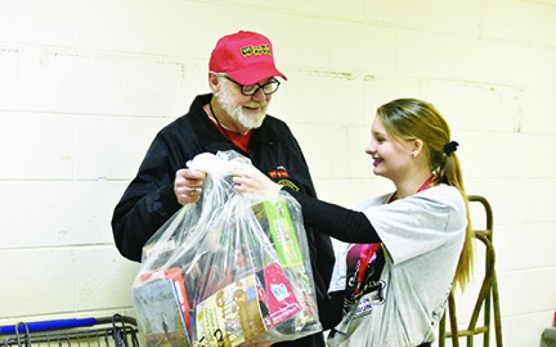 While volunteering at the Toys for Tots distribution, John Evans of Bellview is handed a bag of toys for a family by Jade Stiles. Photo by Samantha Sinclair