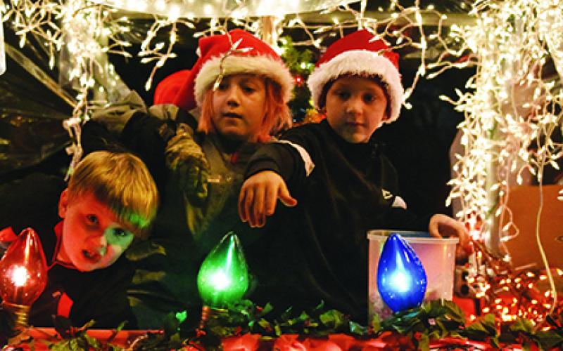 In their snow globe float, Cub Scouts Bradyn Thompson, Zack Bryant and Cale Wilson (from left) look for friends to throw candy to along the parade route Saturday night. Photo by Samantha Sinclair