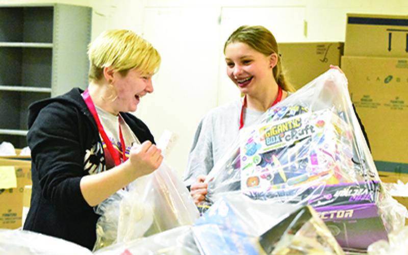 Tri-County Early College High School students Marie Townson and Jade Stiles carry bags of toys they gathered for a family during Toys for Tots distribution Dec. 13. Photo by Samantha Sinclair
