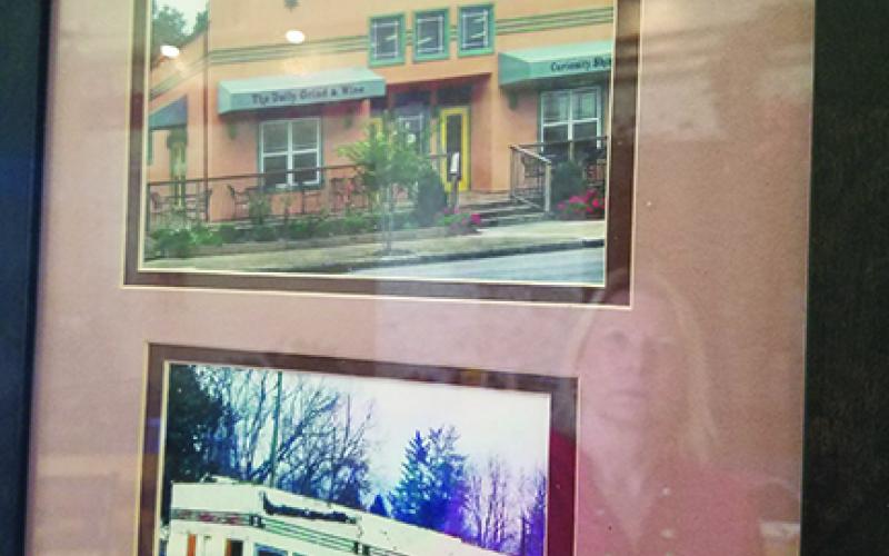 On the wall at FernCrest Winery in Andrews, Jan Olson (reflected) has framed photos that show the building’s past. Photo by Samantha Sinclair
