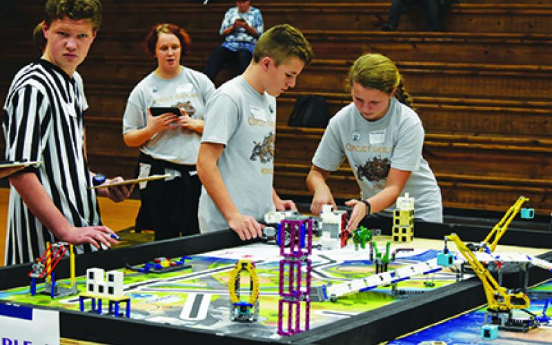 As teammates Paige Black and Lyden Raxter watch and assist, Cece Ward makes adjustments her team’s robot during Murphy Middle School’s final robot performance run in the FIRST Lego League robotics qualifying tournament on Nov. 23 in Blairsville, Ga. Photo by Samantha Sinclair