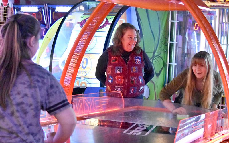 During the Big Brothers Big Sisters Christmas Party at the UltraStar Multi-tainment Center in December, Sallie Sompayrac watches Emily Barnes plays air hockey with her Little. Photo by Samantha Sinclair