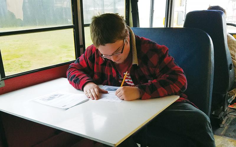Andrew Graves uses one of the tables at the front of the former Bus 101 to complete classwork. Photo by Samantha Sinclair