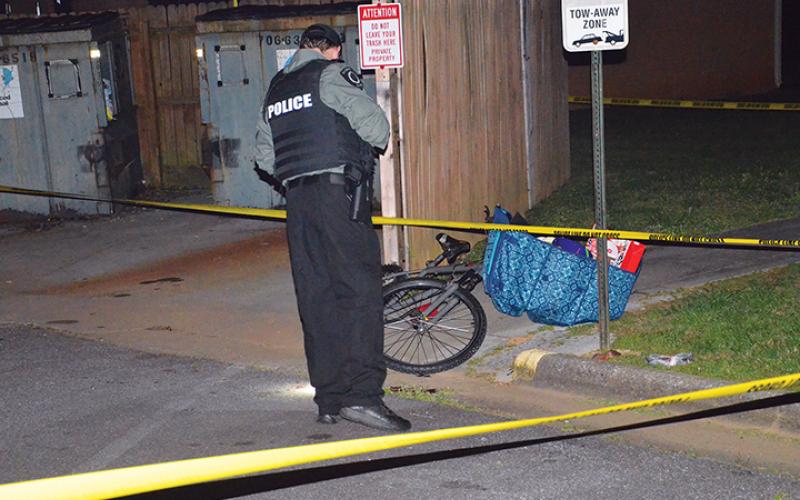 Police examine the area where Charles McTaggart struggled with his killer next to a Dumpster at the Andrews Housing Authority. Photo by Penny Ray