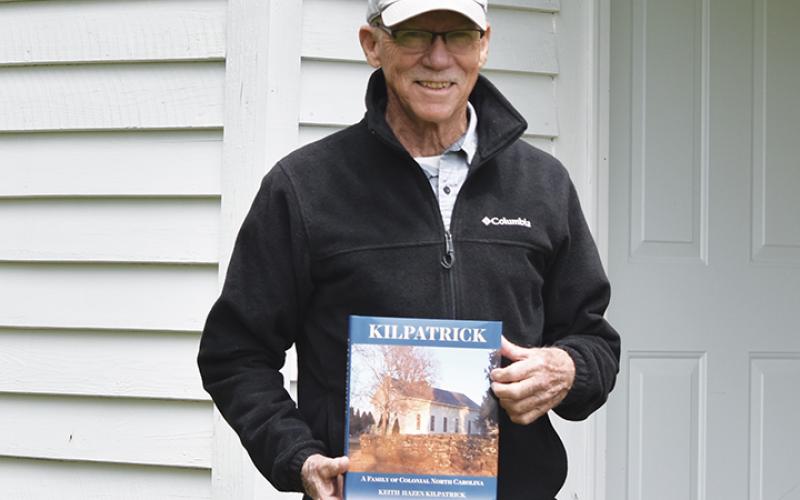 Keith Kilpatrick holds his book, Kilpatrick: A Family of Colonial North Carolina, outside the potato house on his family’s property. Photo by Samantha Sinclair