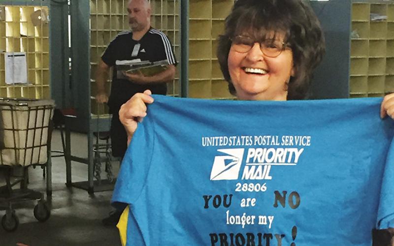 Ava Anderson holds up a shirt she received during her retirement party at the Murphy Post Office.