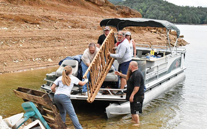 Noah Shatzer/sports@cherokeescout.com Mainspring Conservation Trust outreach associate Rachel Newcomb helps a pontoon boat of retired firefighters unload the trash they picked up around Hiwassee Lake.