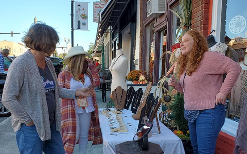 Photo by Samantha Sinclair: Jewelry artisan Cindy Fife talks about her artwork to passers-by at Art Walk Friday nigh.