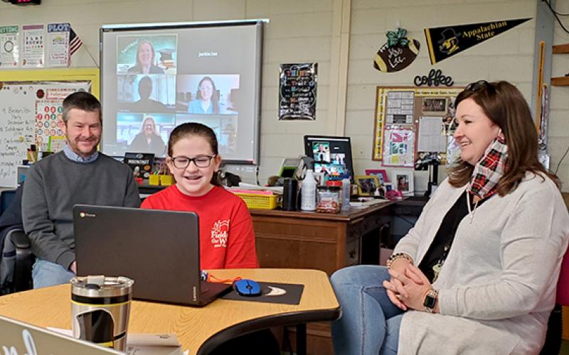 Samantha Sinclair/scoutingaround@cherokeescout.com Abby Lee, with parents Tim and Jackie beside her, listens as College Foundation of North Carolina regional representative Devon McCarthy-James congratulates her during videoconference presentation Feb. 10. On the screen in the background are McCarthy-James, Hiwassee Dam Elementary/Middle School counselor Lauren Grubb, teacher Whitney Tanner and Principal Ruby Cutshaw.