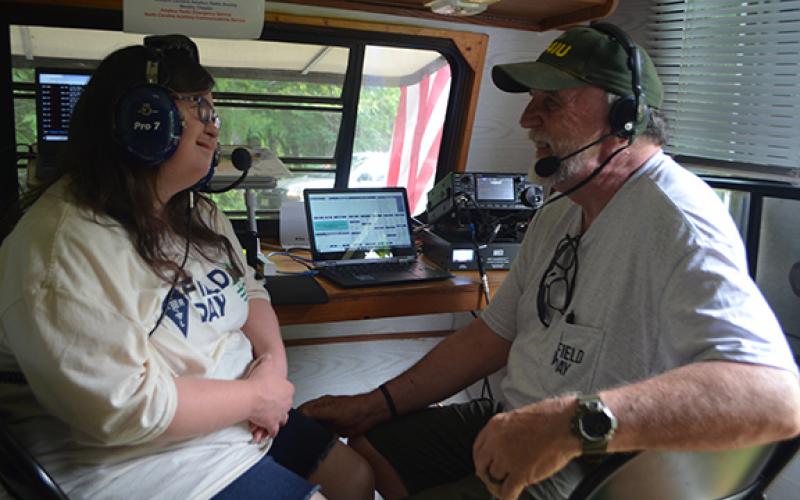 Club President Ron Parks, with daughter Anna Grace Vegas, gets ready to transmit from the Western Carolina Amateur Radio Society’s Field Day on Saturday.