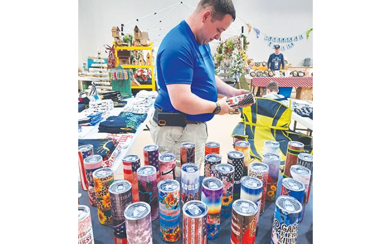 Eric Spalding looks at tumblers and mugs created by vendors Christina Brown and Jennifer Spalding during the First Free Will Baptist Church Arts & Craft show in Hayesville