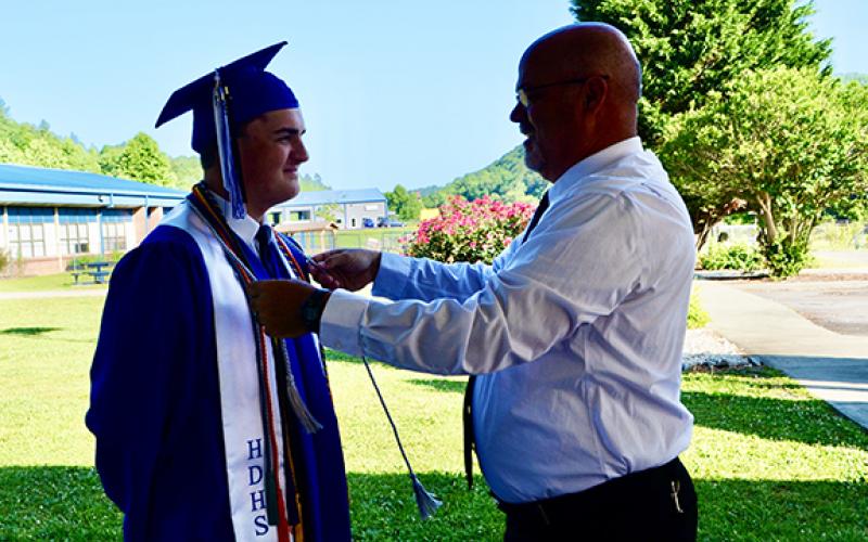 Graduating senior Tyler Robertson gets help with his cords from Principal Daniel McNabb on Saturday morning before the Hiwassee Dam High School Class of 2023 graduation ceremony.