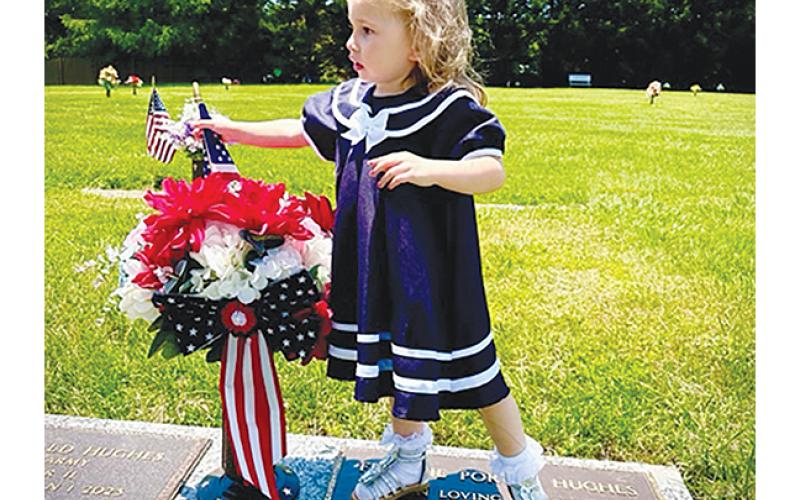 Lisa Adams/ Contributing Photographer To honor him and his service in the U.S. Army on Memorial Day, Frankie Hughes placed a patriotic bow on the grave of her late husband, Don Hughes, along with her great-great- granddaughter, Leighton Hughes. Hughes, who was born on Jan. 17, 1927, and passed away on Jan. 1, 2023, was well known as an electrician at Hughes Electric; his family called him a very kind and caring man who loved his family, and also had a great sense of humor and loved to joke and laugh.