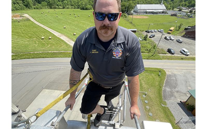 Peachtree Fire Chief Jordan Messer stands at the top of a fully extended 70-foot aerial ladder truck at the fire station on May 19.