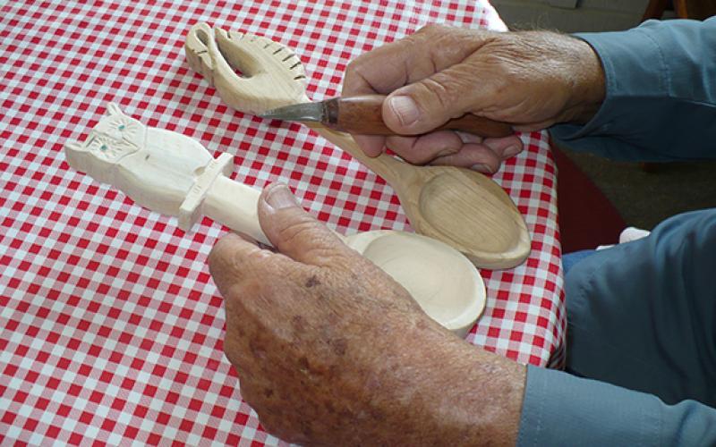 Wally Avett/Contributing Photographer The hands of instructor Lee Crews cradle two carved wooden spoons and one of his self-made knives, which he provides free for use by his students.