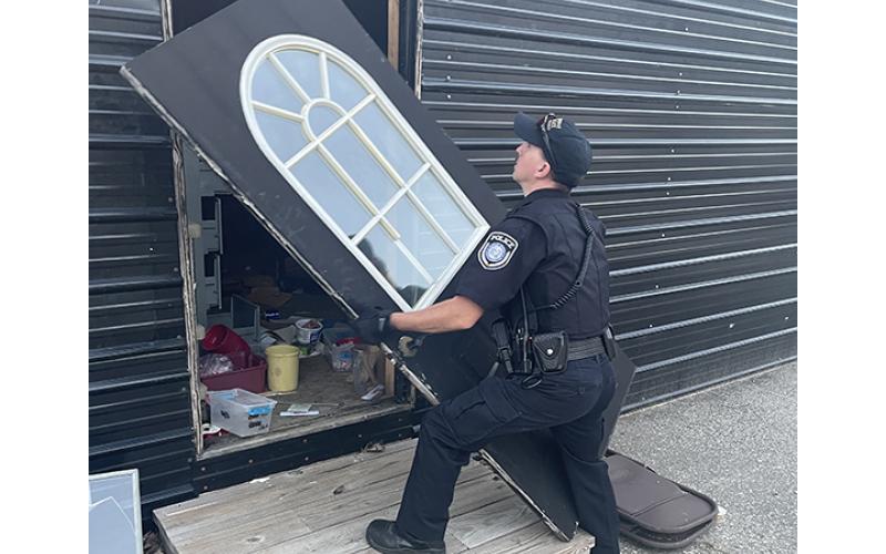 Randy Foster/editor@cherokeescout.com Murphy police Cpl. Adam May attempts to reinstall a door that someone had broken off of its hinges outside an empty commercial building in Murphy on Friday.