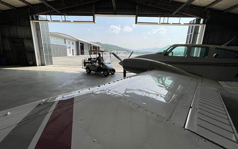 Randy Foster/editor@cherokeescout.com Airport Manager Chris Williams, at the controls of a golf cart, pulls a private airplane from its hangar at Western Carolina Regional Airport in Andrews.