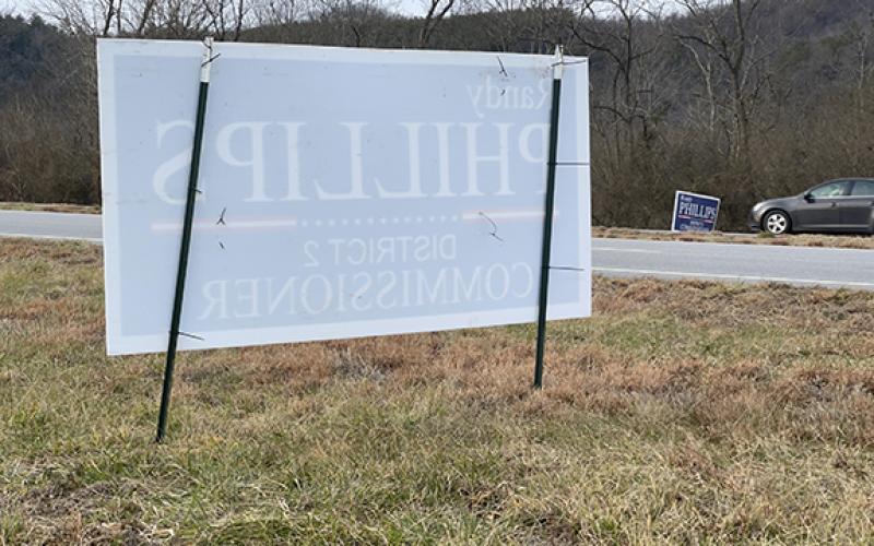 Cherokee County Commissioner Randy Phillips’ campaign signs placed in the right-of-way on both sides of U.S. 19/74/129 near Western Carolina Regional Airport appear to violate state law, which allows placement of campaign signs no sooner than 30 days before one-stop voting begins on Feb. 15.