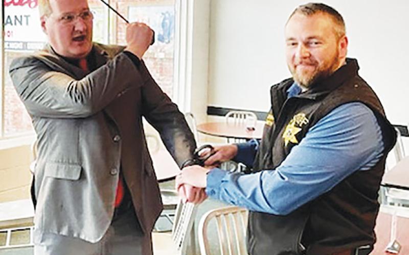 Mayor Tim Radford wields an umbrella at Cherokee County Sheriff Dustin Smith showing his displeasure at being arrested during the Rotary Club of Murphy’s Jail & Bail fundraiser, which was held at Downtown Pizza in Murphy on March 1.