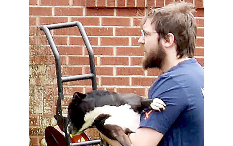 Tylor Matheson reunites with the family dog, “Tudy,” which had been leashed to the front porch railing when the fire erupted. Deputy Tyler Faggard cut the leash to free the dog from the flames and smoke.