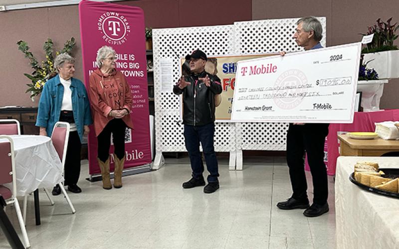 David Brown/dbrown@cherokeescout.com Ray Calles, retail store manager for T-Mobile, talks about the Sharing Center’s $19,996 grant Thursday afternoon in the Murphy First Baptist Church Fellowship Hall. To his left (from left) are grant writer Karen Borchers and food bank board President Sande Kimball; to his right is board vice president Steve Runyan, holding the big check.