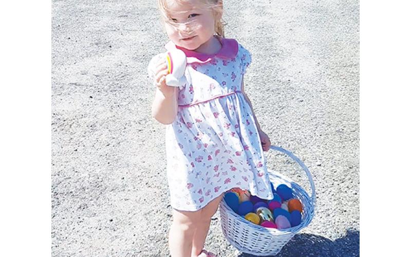 Little Rachel Boring, 2, of Hiwassee Dam, happily held up one of the treats in her basket Saturday at Shepherd of the Mountains Church’s annual Easter egg hunt in Murphy. The toddler was busy filling her basket, while also trying to keep the spring sun out of her eyes.