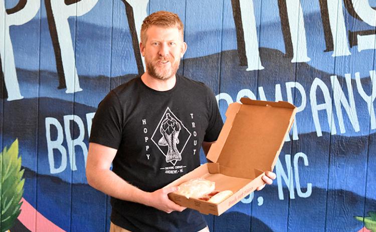Tommy Rodeck holds a box of Take & Bake pizza, his newest to-go menu item at Hoppy Trout Brewing Co. Photo by Samantha Sinclair