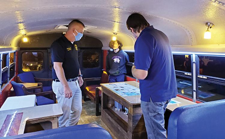 Cherokee County Board of Education member Joe Wood (left)  listens as student Jason Wolfe and teacher John Worden explain the features of the district’s new Parent Engagement Bus, or the LearnIn Bus.