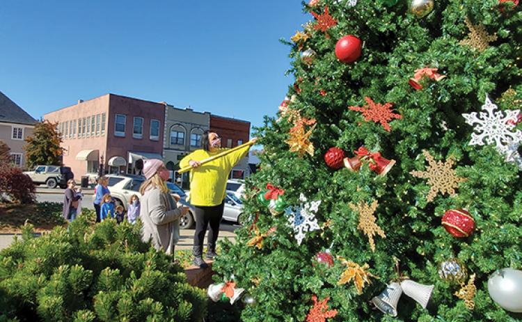 The Tilford family of Hiwassee Dam stops to watch as Jordan Mixon and Jill Kernea of the Festive Fairies fluff out Murphy’s Christmas Tree. Photo by Samantha Sinclair