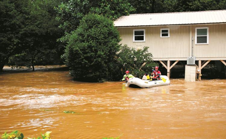 Clay County Swift Water Rescue team members Tim Noland and Henry Angelopulos take an unidentified woman from her Brasstown home, which was surrounded by flood water, to the safety of dry ground on Aug. 17.