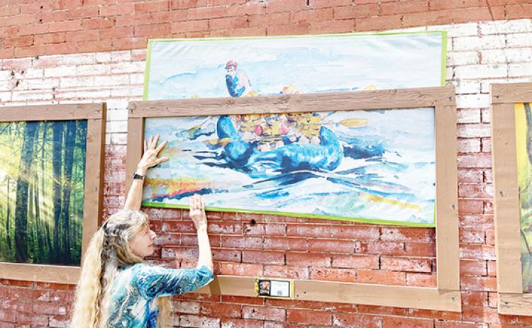 Abigail Hickman/Staff Correspondent Debra Vanderlaan of the Valley River Arts Guild elevates local artist Marie Spaeder Haas’ work as part of the Main Street Community effort.
