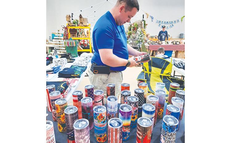Eric Spalding looks at tumblers and mugs created by vendors Christina Brown and Jennifer Spalding during the First Free Will Baptist Church Arts & Craft show in Hayesville