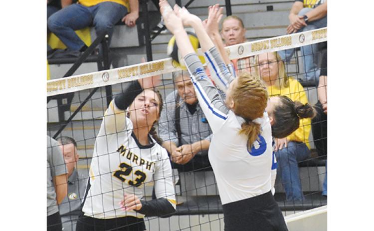 Justin Fitzgerald/sports@cherokeescout.com Murphy’s Liv Payne tries to hit the ball through the block of Cherryville’s Carson Reid (left) and Rileigh Kiser (right) during the Lady Bulldogs’ straight-set win over the Lady Ironmen on Saturday in the first round of the state playoffs.