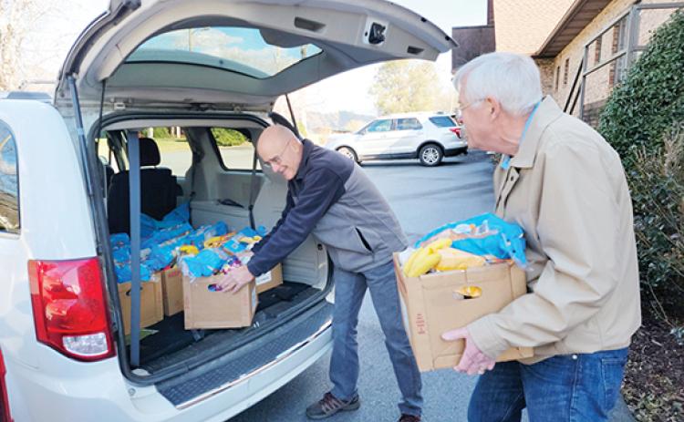 George Bodossian and Ken Brown load food into vehicles for the ministry. 