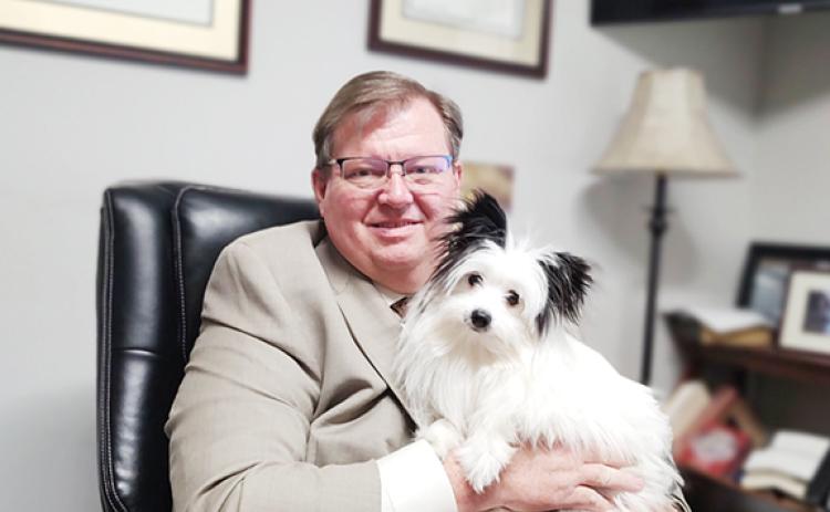 Abigail Blythe Batton/Staff Correspondent Rich Cassady sits at his desk with Lucy, his beloved “palmapoo” – his term for a Pomeranian poodle mix – during a busy day as an area defense attorney.